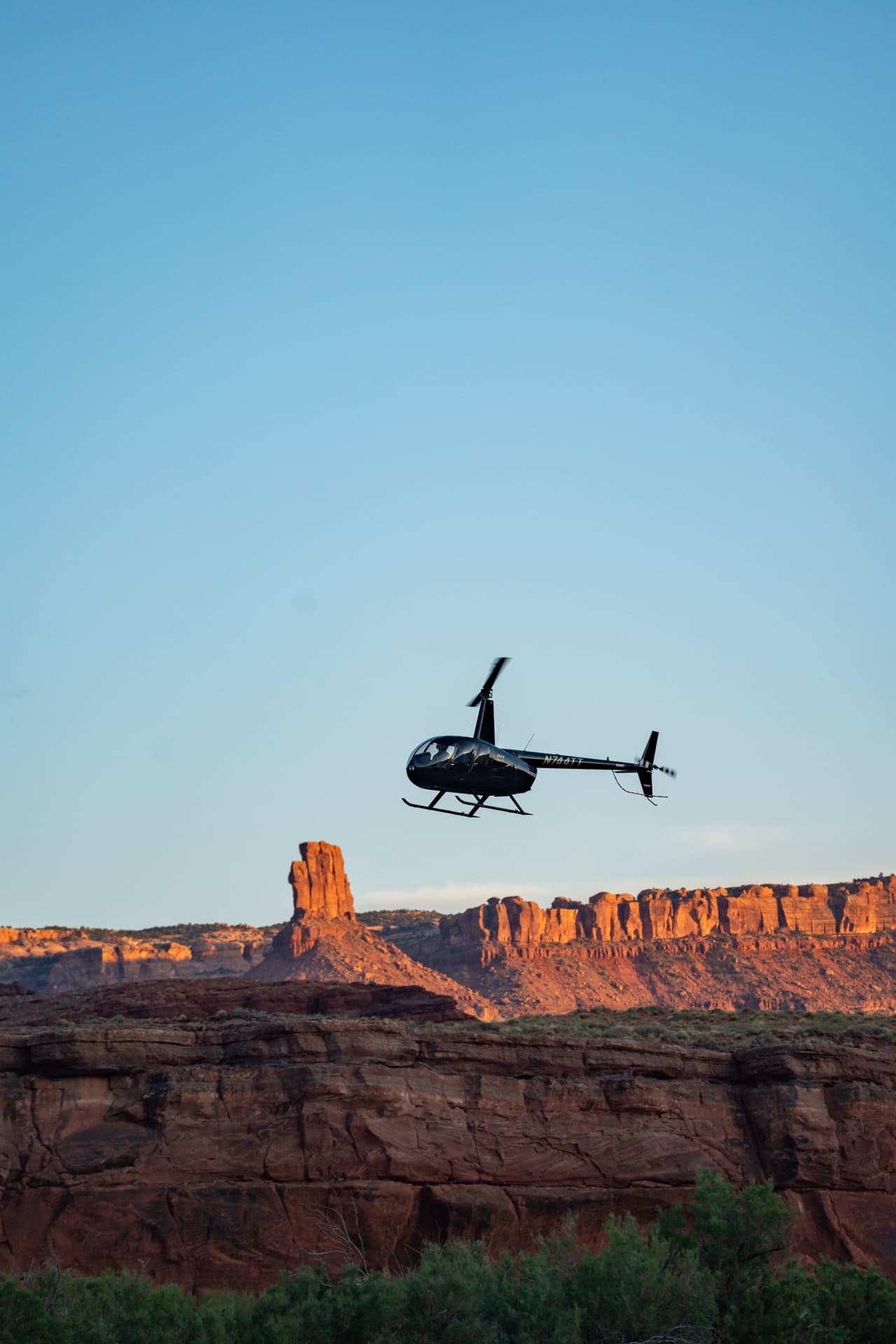 Helicopter flying over canyon walls at sunset