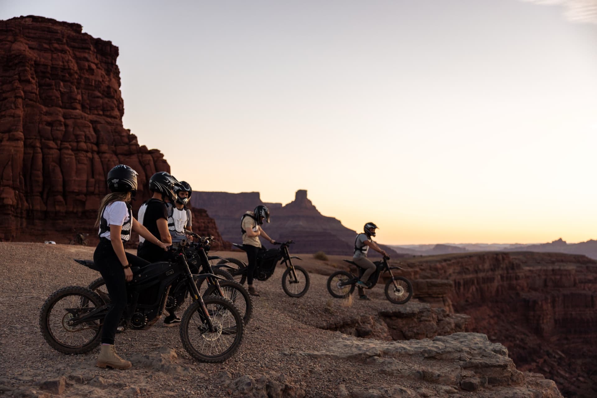 E-bikers on canyon rim overlooking Moab at sunset